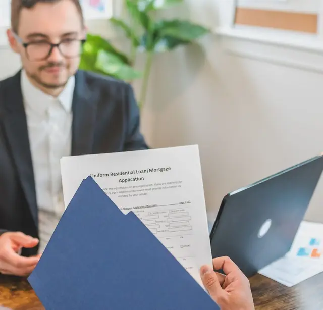 Loan officer holding a Uniform Residential Loan/Mortgage Application, the source record behind a HMDA LAR entry